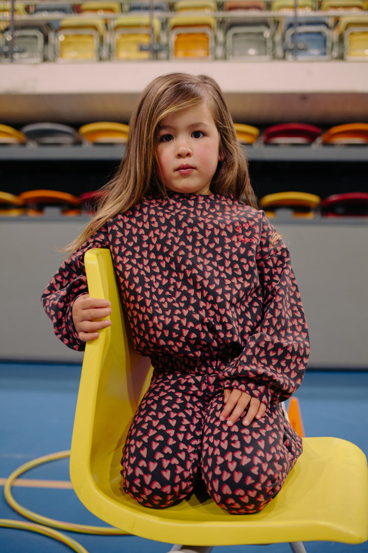 Stains & Stories Hearts All Over Sweatshirt and pants model seat